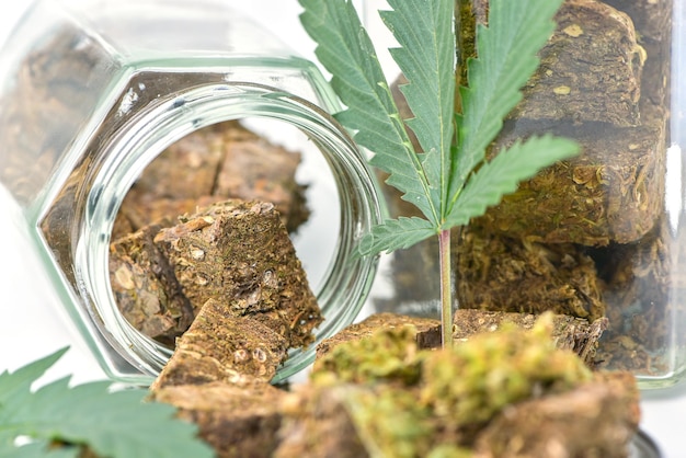 Getrocknetes Marihuana in einem Glas mit grünen Marihuana-Blättern und Rollen auf weißem Hintergrund Medizinische Marihuana-Apotheke Alternative Medizin Cannabis-Plantage für Medizin- und Geschäftskonzept
