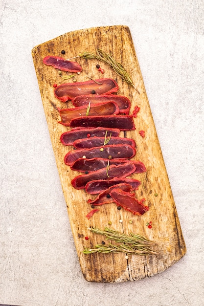 Getrocknetes Rinderfilet mit trockenem Rosmarin und Pfeffer mischen auf hölzernem Brett der Weinlese