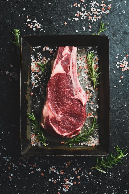 Foto getrocknetes rohes rindfleisch steak auf dem knochen auf einem metalltablett mit salz, gewürzen und kräutern