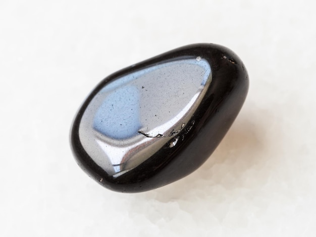 Getrommelter schwarzer Obsidian-Edelstein auf Weiß