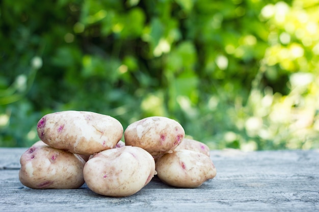 Gewaschene junge Kartoffeln auf hölzernem Hintergrund, Nahaufnahme