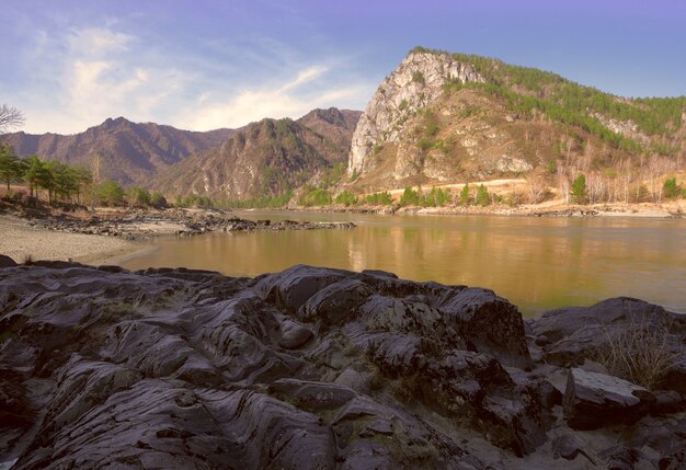 Gewellte geschichtete Felsen am Ufer eines Bergflusses Geologische Attraktion