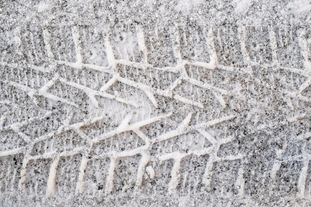 Gewellte Spur des Autoreifens auf Schnee im Winter für den abstrakten strukturierten Hintergrund