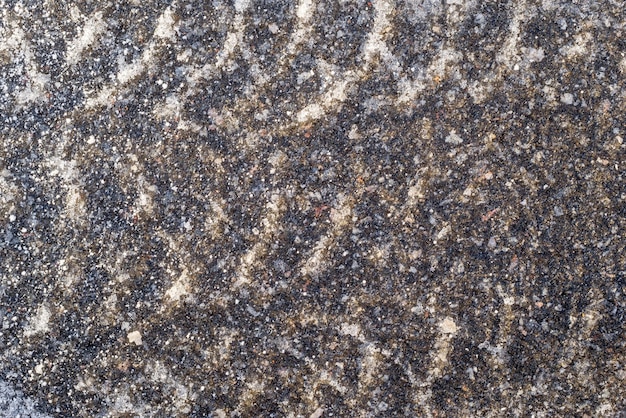 Gewellte Spur des Autoreifens im Winter auf Asphalt mit Eis für den strukturierten Hintergrund