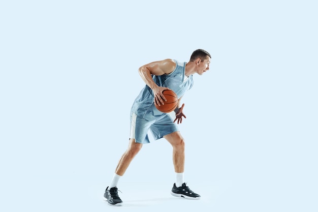 Gewinner. Junge kaukasische Basketballspieler des Teams in Aktion, Bewegung im Sprung isoliert auf Blau.