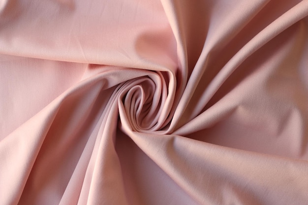 Gewirbelter rosa Satinstoff mit eleganten Falten als Hintergrund, weiches Textilmaterial zum Nähen und