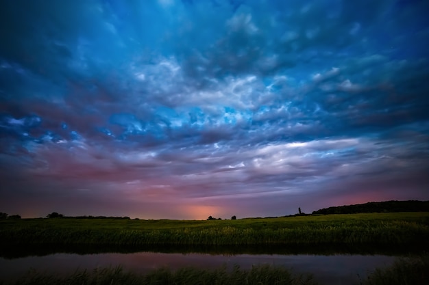 Gewitterwolken am Himmel nach Sonnenuntergang auf dem Fluss