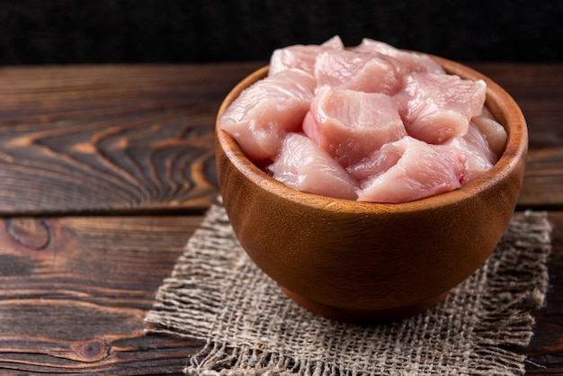 Gewürfelte rohe hühnerbrust oder filets auf dunklem hölzernem hintergrund.