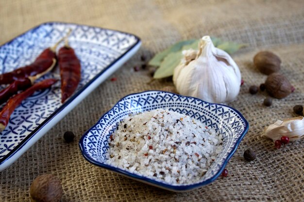 Gewürze, weiße, schwarze und rote Paprika, Meersalz, Knoblauch, Tomaten und Chili auf einem rustikalen Leinenhintergrund