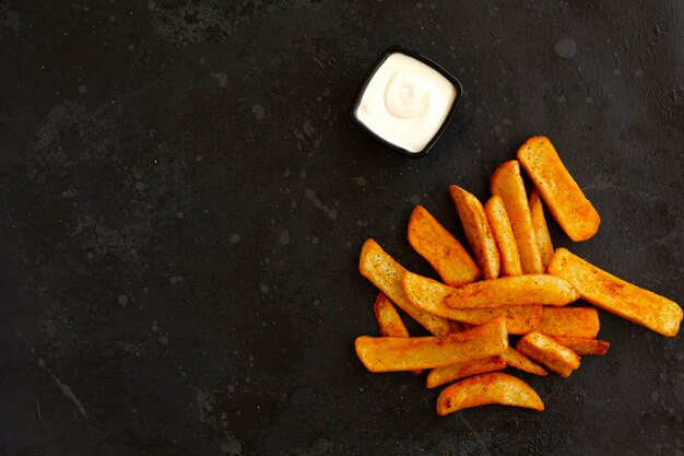 Gewürzte französische Kartoffeln und Mayonnaise auf einem dunklen Hintergrundkopierraum