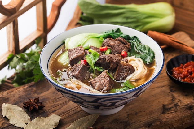 Gewürzte rote Suppe mit Rindfleisch-Nudeln in einer Schüssel auf einem Holztisch