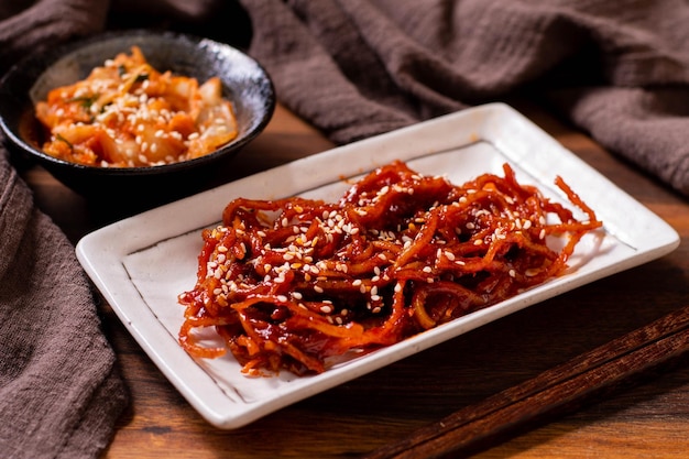 Gewürzter, getrockneter Tintenfisch (Ojingeochae muchim) mit Kimchi auf Holztisch