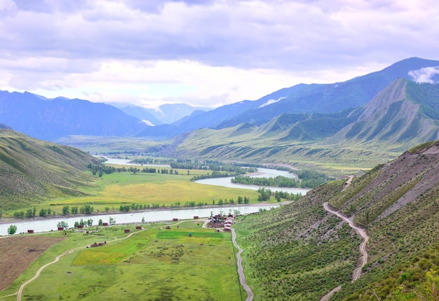 Gewundenes Flussbett, umgeben von Bergen unter einem blauen bewölkten Himmel Sibirien Russland