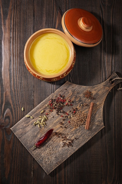 Ghee em uma panela de cerâmica e um conjunto de especiarias para a preparação de Garam masala indiano. Vista do topo.