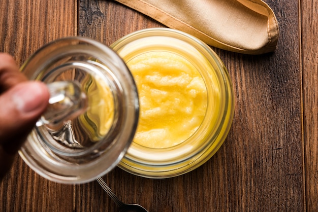 Ghee oder geklärte Butter hautnah in Holzschale und Silberlöffel, selektiver Fokus