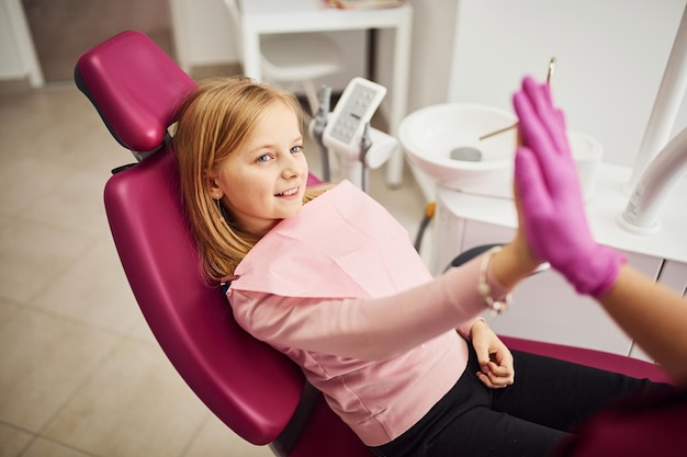 Gibt High Five Kleines Mädchen, das Zahnarzt in der Klinik besucht Konzeption der Stomatologie