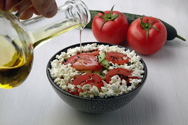 Gießen Olivenöl Salat von frischen Tomaten-Gurken