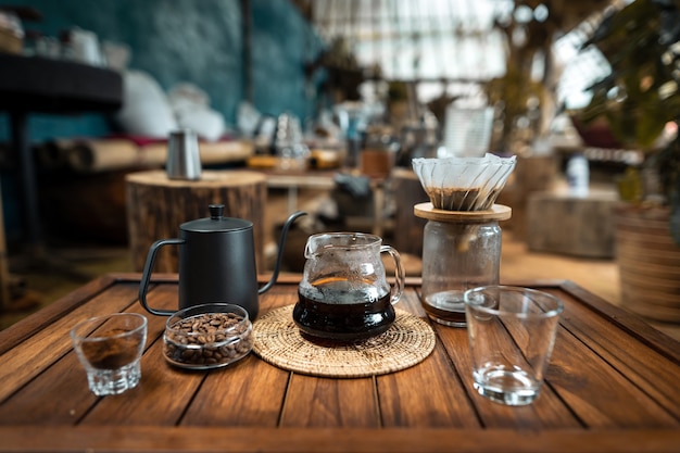 Gießen Sie heißes Wasser in den Kaffee., tropfen Sie Kaffee auf einem Holztisch zu Hause