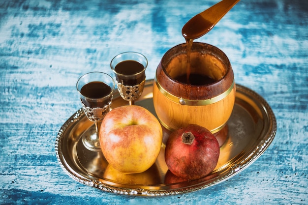 Gießen Sie Honig auf Apfel und Granatapfel mit Honigsymbolen des jüdischen Neujahrs - Rosh Hashanah.