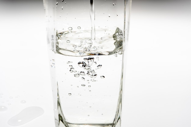Gießen Sie Trinkwasser in das hohe Glas