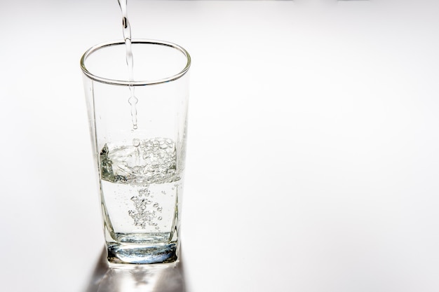 Gießen Sie Trinkwasser in das hohe Glas