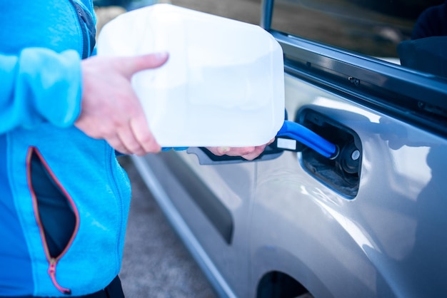 Gießen von Adblue in das Auto Männlicher Fahrer, der seinem Auto Diesel-Abgasflüssigkeit hinzufügt