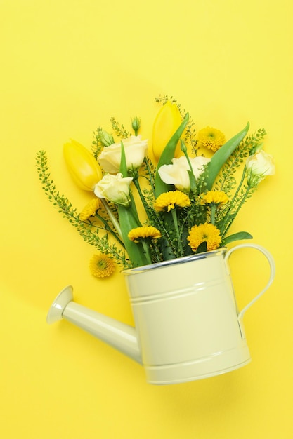 Gießkanne mit Blumen auf gelbem Grund