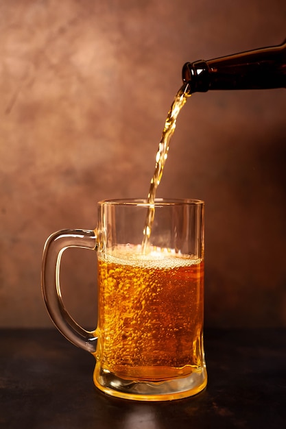 gießt Bier in ein Glas auf einem alten Stein