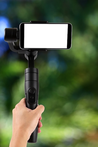 Gimbal. Jovem usando estabilizador para celular e filmando a floresta. Foco seletivo