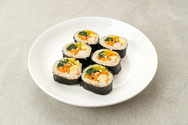 Gimbap coreano enrollado hecho de arroz, pepino, atún, zanahoria, salchicha, cangrejo y palito.