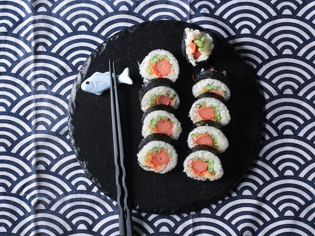 Gimbap de rolo coreano (kimbob ou kimbap) feito de arroz branco cozido no vapor (bap) e vários outros ingredientes, como kyuri, cenoura, salsicha, pau de caranguejo ou kimchi e embrulhado com lavadora de algas marinhas