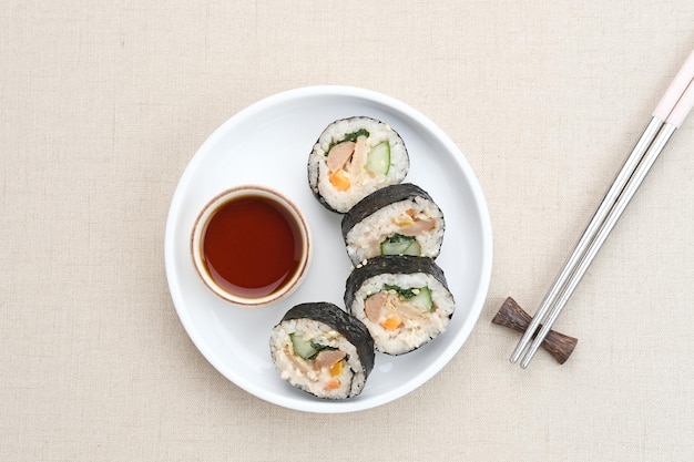 Gimbap enrollado coreano, hecho de arroz, pepino, atún, zanahoria, salchicha, palito de cangrejo.