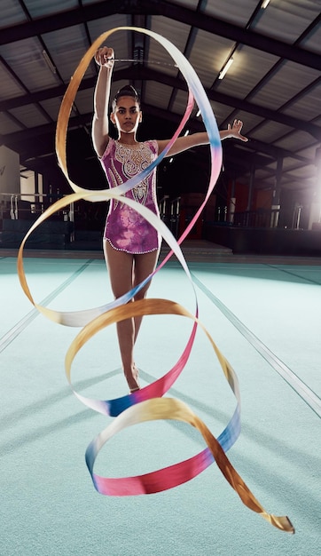 Foto gimnasia, entrenamiento deportivo, danza de la cinta en la arena y la práctica de la atleta rítmica