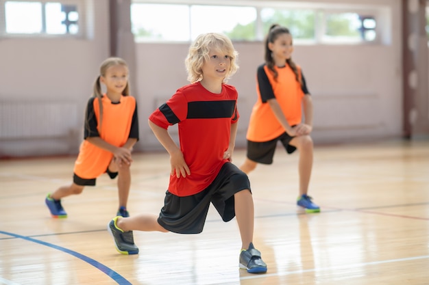 En el gimnasio. Niños haciendo ejercicio en el gimnasio y haciendo lanzamientos hacia adelante.