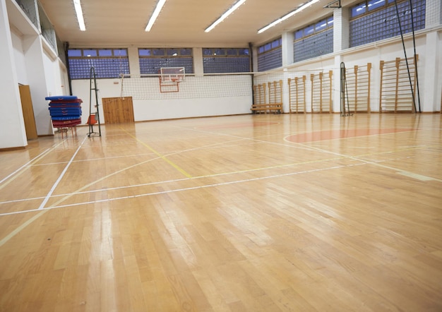 un gimnasio con un piso de madera y una bolsa de gimnasio roja en el suelo