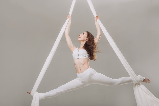 Gimnasta femenina haciendo acrobacias aéreas de seda.