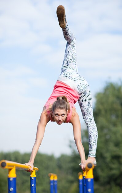 Gimnasta joven ágil que equilibra en barras cruzadas