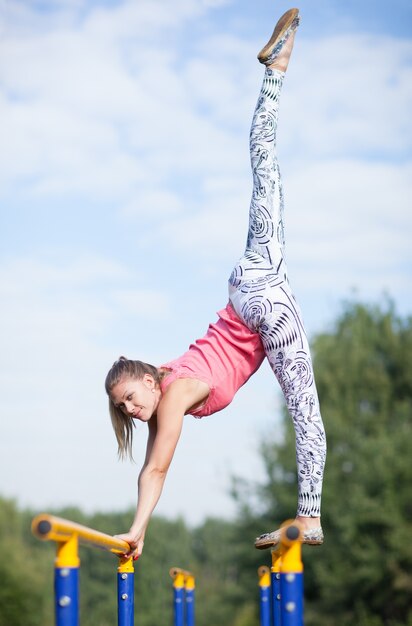 Gimnasta joven ágil que equilibra en barras cruzadas