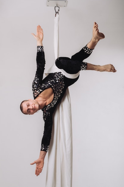 Gimnasta masculino haciendo acrobacias aéreas de seda.