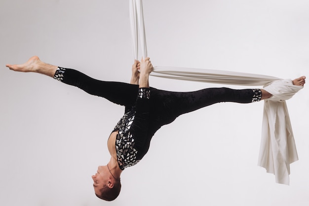 Gimnasta masculino haciendo acrobacias aéreas de seda.