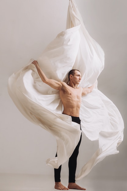 Gimnasta masculino posando con cintas de seda aéreas