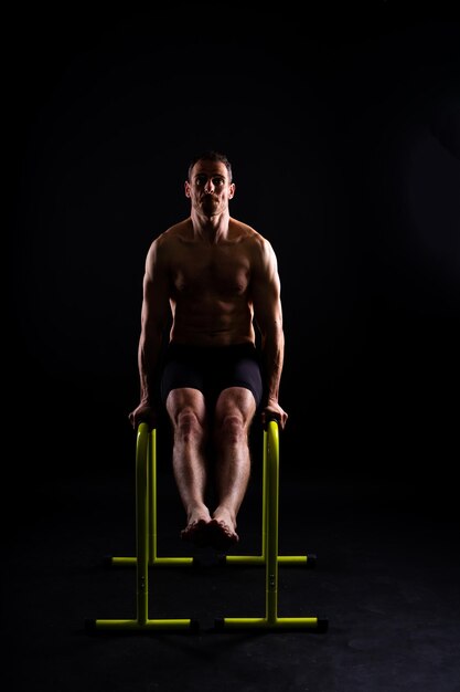 Gimnasta masculino realizando un handstand en barras paralelas en un estudio