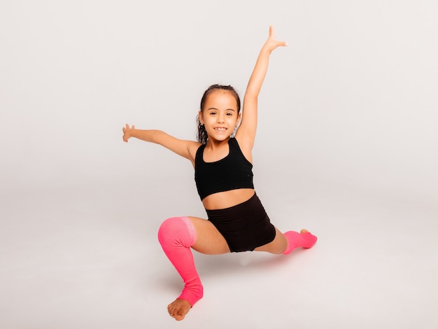 Gimnasta niña sobre un fondo blanco. ejercicios deportivos. extensión. flexibilidad. aeróbicos