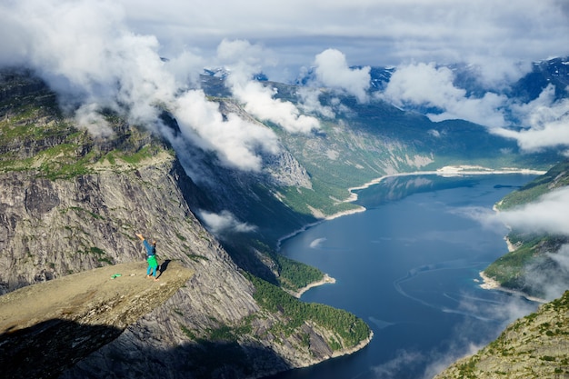 Foto gimnasta de pie sobre sus manos en el borde con el fiordo en el fondo cerca de trolltunga. noruega.