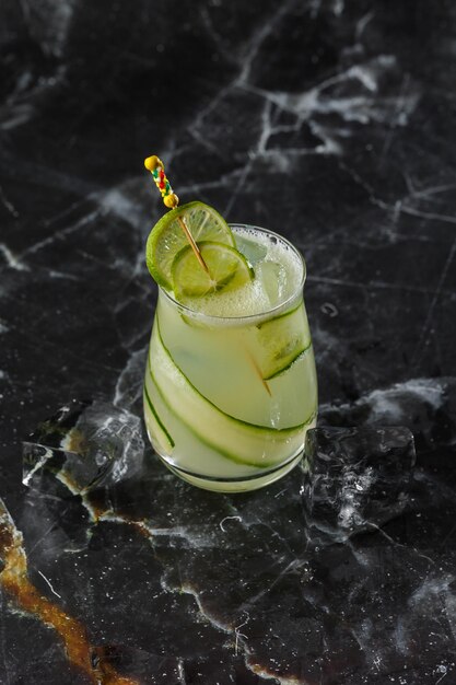 Gin-Gimlet-Cocktail, garniert mit Gurke Grüner Alkoholcocktail Mit einer Gurke auf schwarzem Hintergrund