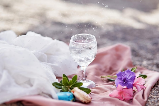 Gin Tonic Cocktail im Weinglas am Strand mit Blumen Zarte Seidenmaterialien und Bokeh-Hintergrund Erfrischendes Sommerkonzept Hochwertiges Foto