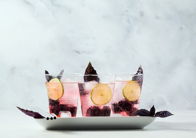 Gin tonic con moras y hojas de albahaca morada. cóctel refrescante de verano