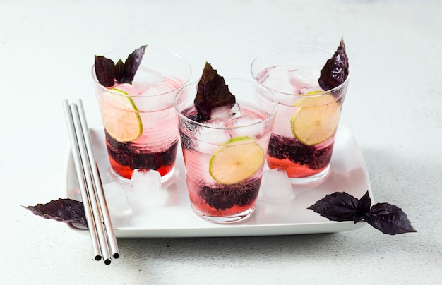 Gin tônico com amoras e folhas de manjericão roxo. cocktail refrescante de verão