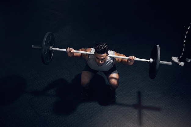 Ginásio escuro de agachamento com barra e treinamento esportivo masculino e fitness de levantamento de peso pesado no clube de saúde Acima do atleta fisiculturista indiano e exercício corporal força muscular e forte motivação