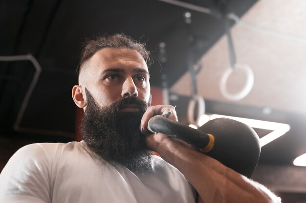 Ginásio. Treinamento de homem barbudo. Kettlebell.